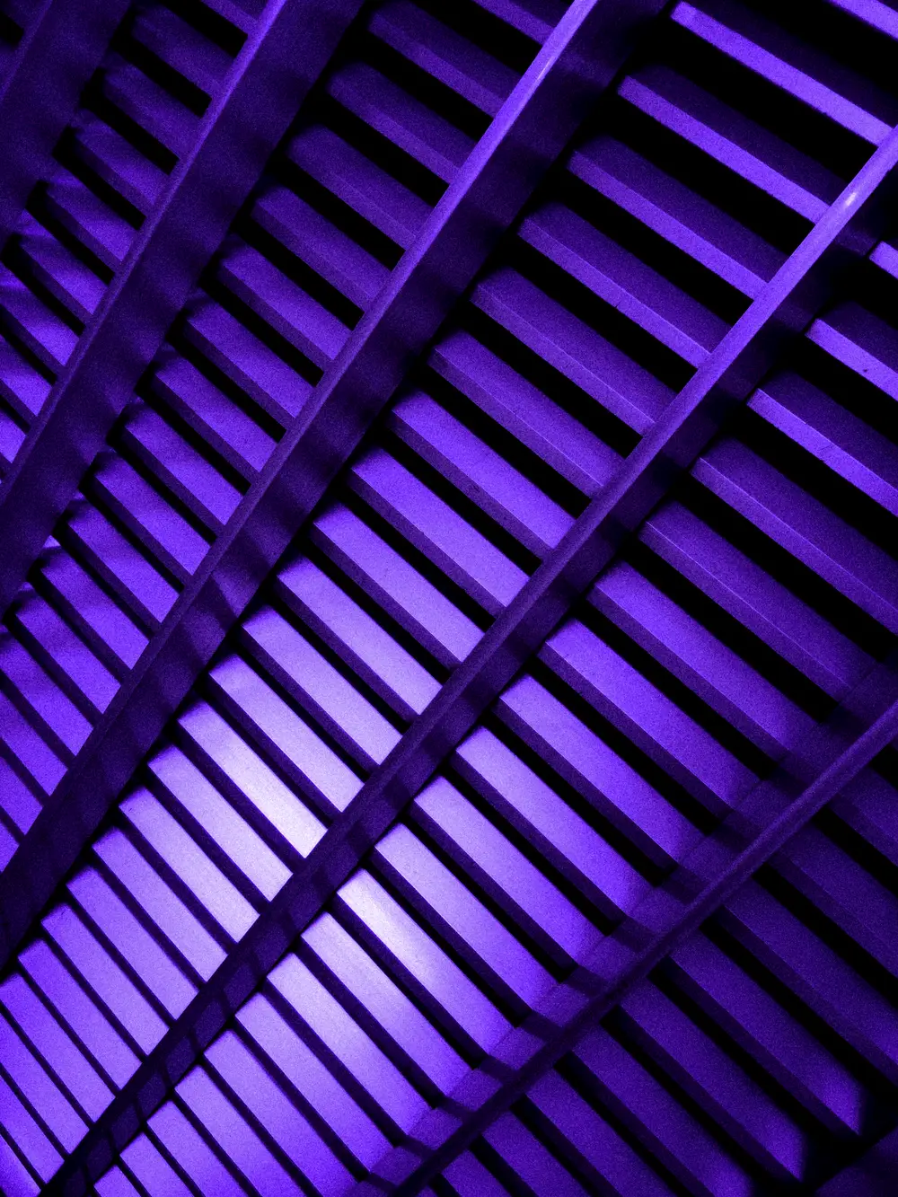 Black-and-white view along a row of tall vertical metal panels with blurred lights.